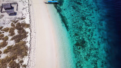 A drone shot of a boat anchored to pink beach on an island near Maumere, Indonesia. There is a...