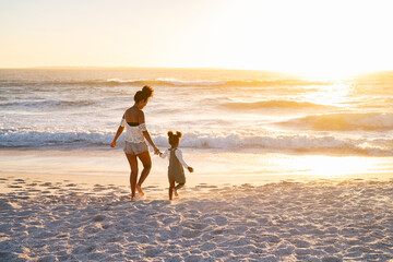Black lovely mother and daughter walking on beach at sunset - Powered by Adobe