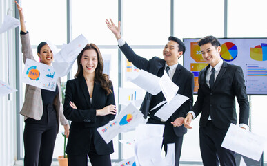 Group of Asian happy excited cheerful professional successful businessman and businesswoman in formal business suit standing smiling throwing paperwork documents celebrating job success deal done