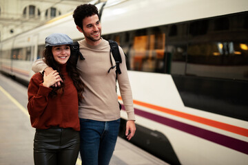 Beautiful couple at railway station waiting for the train. Young woman and man waiting to board a train.