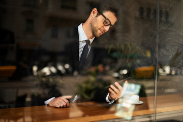 Handsome businessman using the phone in cafe. Young elegance man enjoy in fresh coffee.