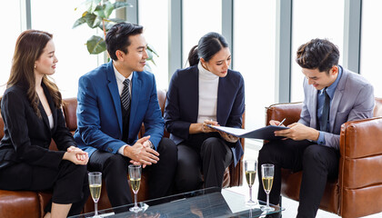 Asian professional successful male businessman customer in formal business suit sitting on leather sofa signing signature on contract agreement while happy company sales staffs smiling when job done © Bangkok Click Studio