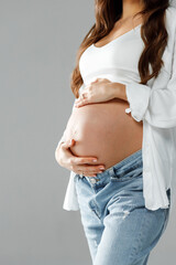 Happy pregnant woman in a studio holding her stomach and wearing bright shirt