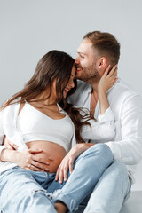 Beautiful couple of a man and pregnant woman smiling happily hugging and kissing together