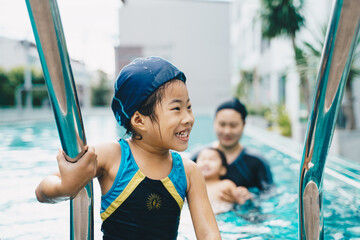 Little asian kindergarten girl practice swim in swimming pool