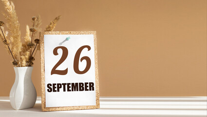 september 26. 26th day of month, calendar date.White vase with dead wood next to cork board with numbers. White-beige background with striped shadow. Concept of day of year, time planner, autumn month