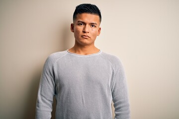 Young handsome latin man wearing casual sweater standing over isolated white background Relaxed with serious expression on face. Simple and natural looking at the camera.