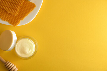 Moisturizing skin care cream with honey extracts on yellow table
