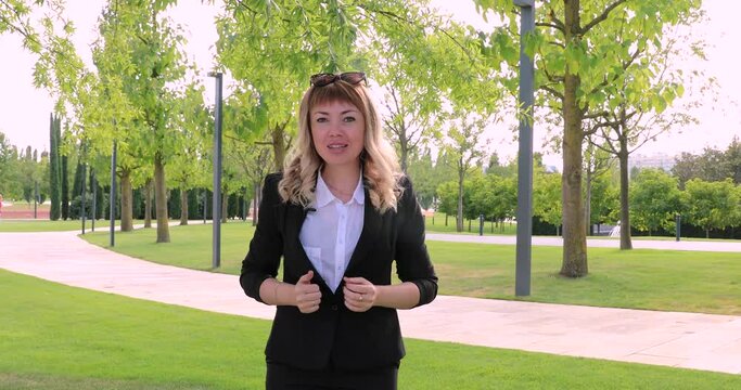 beautiful young woman journalist tells news. a lady's business in a park on the street. reporting. TV