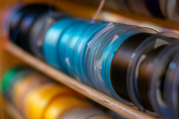 Many colorful ribbons stacked on a shelf to be sold in store, ribbon sale in a shop, creative handcraft or sewing accessories in rolls. Selective focus with shallow depth of field.