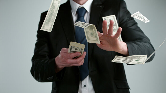 Close-up of a young businessman throwing out money banknotes