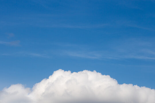 Fluffy white clouds at the bottom with the blue sky at the top. Sky background with empty space for text