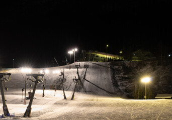 Slopes at a ski resort lit up at night for evening skiing. 