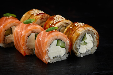 Traditional Japanese rolls with salmon and smoked eel in set on black background.