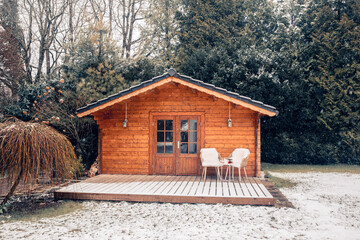 Nice wooden hut in a garden with snow. Garden shed with chairs in winter. Winter mood. Drinking tea outside by cold in winter.  snow in Germany. garden in winter. holiday house