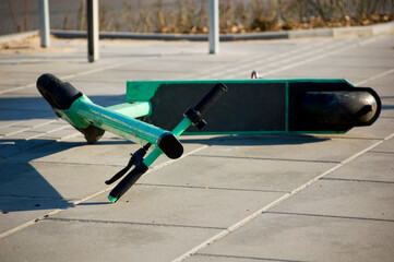 Broken electric scooter lying on the sidewalk.