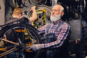 Fototapeta na wymiar Grandfather with his grandson repairing bicycles in workshop