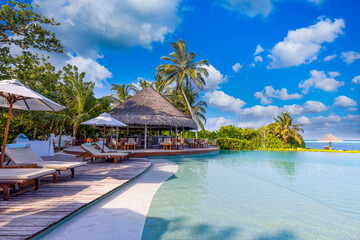 Recreational tourism landscape. Luxurious beach resort with spa swimming pool and beach chairs or leisure loungers under umbrellas with palm trees sky. Summer travel vacation background. Wellbeing - obrazy, fototapety, plakaty