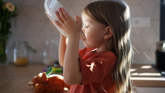Little girl drinking soup from plate at home.