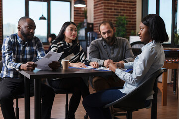 Employers sitting at desk table during interview meeting in startup company office. Managers analyzing cv resume hiring candidate for human resources job while sitting in meeting room.