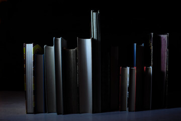 Row of hardback books on wooden table on dark background. Back to school,education,reading. Copy...