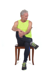 front view of a man in sportswear tights and fluorescent yellow  sleeveless sitting on chair look down on white background