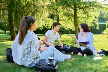 Group of high school students with female teacher, on campus lawn