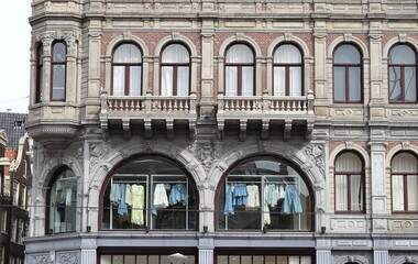 Fototapeta na wymiar Amsterdam Dam Square Historic Building Facade Close Up with Clothing Hanging in the Windows, Netherlands