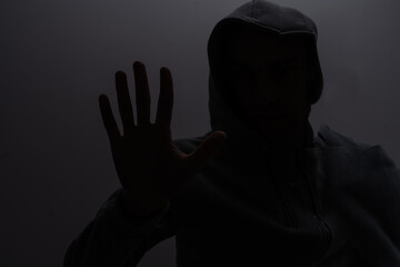 Studio portrait of a man in a hood, a shadow hides his face. Anonymity shadow economy and evasion from the law