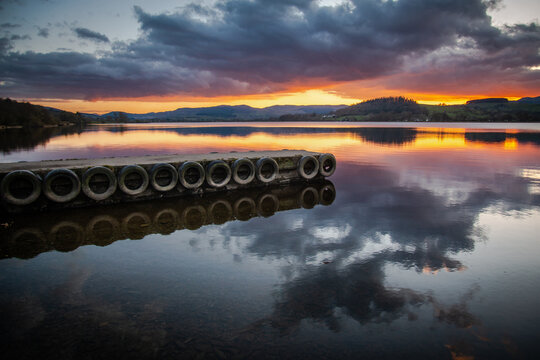 Reflections of clouds over a jetty in Lake Bala at sunset, Gwynedd, Wales, UK