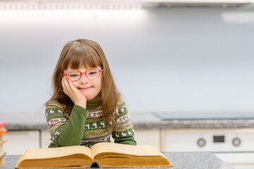 A girl with down syndrome reading a book at home. Family education for children