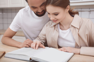 Fototapeta premium Couple in love in the kitchen reading a recipe book