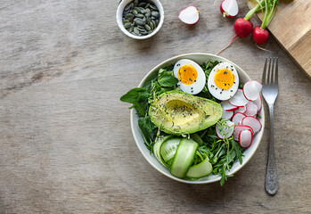 Summer healthy food. Green keto salad with eggs, avocado, radish, and cucumbers. Copy space for text or recipe.
