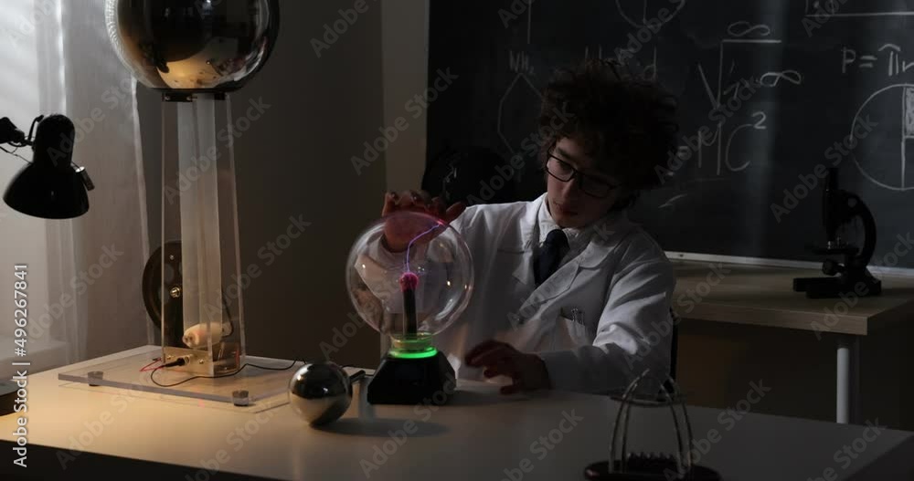Wall mural schoolboy experimenting in physics class. young student doing physics experiment in the classroom