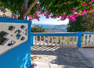 Road with a view, under the shade of a bougainvillea with dark purple flowers. Above the parapet...