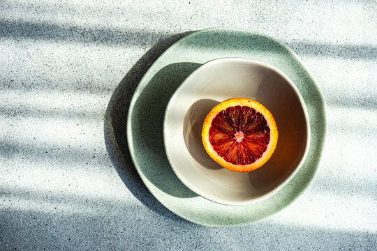 Overhead view of half a Sicilian blood orange in a bowl in sunlight