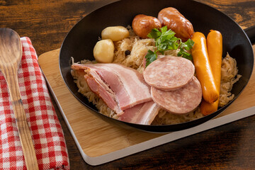 close-up Choucroute garnie (French for dressed sauerkraut) is an Alsatian recipe for preparing sauerkraut with sausages and other cured meats and charcuterie, and often potatoes.