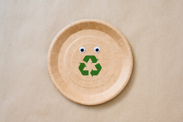 Biodegradable paper plate with eyes and recycling sign. The concept of a call for environmental protection.