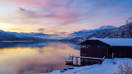 A magical sunset over the lake in Alps. Sky is pink, orange, yellow and blue. On the side there is...