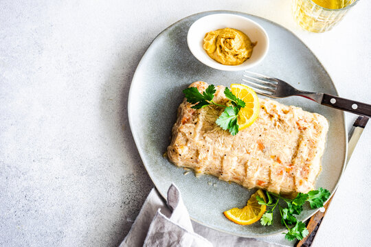Chicken aspic pate on a plate with parsley, lemon, mustard and a glass of white wine