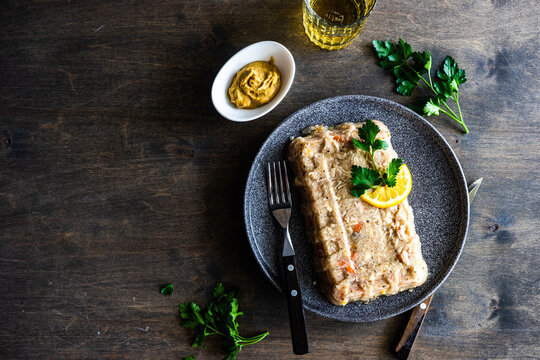Chicken aspic pate on a plate with parsley, lemon, mustard and a glass of white wine