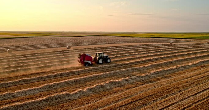 Tractor baling hay on harvested wheat field