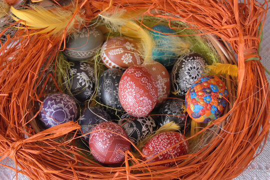 A traditional dyed colourful Easter egg in a basket with feathers in Poland called pisanka or kroszonka