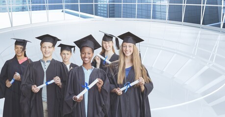 Composite image of group of graduates holding their degrees against office interior in background