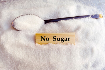 Spoon with white sugar and wooden blocks with no sugar text