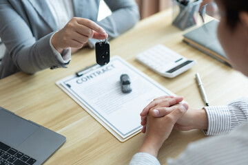 Insurance concept the car dealer explaining the conditions of the car while showing a car key to his client