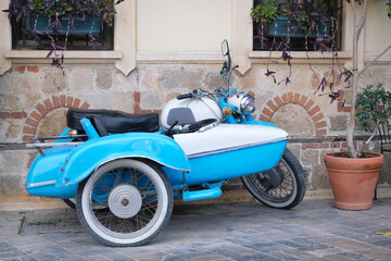 Unusual vehicle blue  vintage restored motorcycle in the historical center of the city against the background of an ancient building
