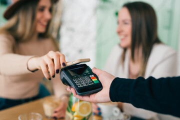 woman paying contactless with her smartphone in cafeteria