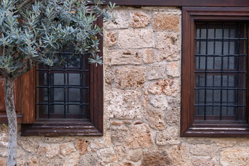 Beautiful old windows with wooden frames and grate on an ancient stone building as a background