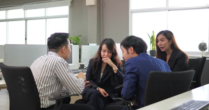 Young Asian business group talking, gossip about the boss and having fun in office.